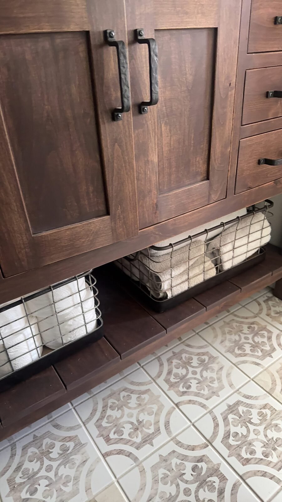 Custom dark walnut bathroom vanity with patterned tile floor by RCV Construction
