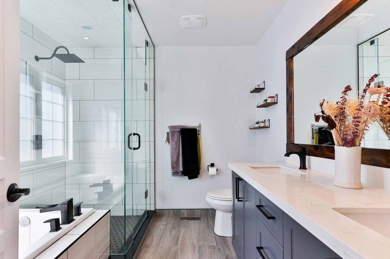 Bathroom remodel with glass shower soaking tub custom vanity and walnut mirror frame by RCV Construction
