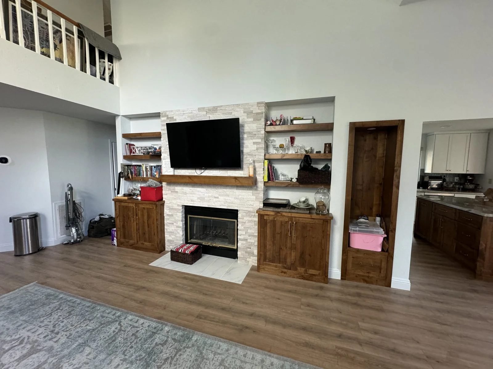 Finished custom knotty alder built-in fireplace wall with floating shelves flanking cabinets and stone tile surround Reno NV