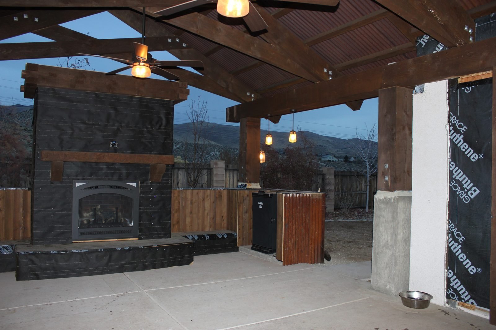 Covered outdoor patio timber frame fireplace outdoor kitchen at dusk Reno NV
